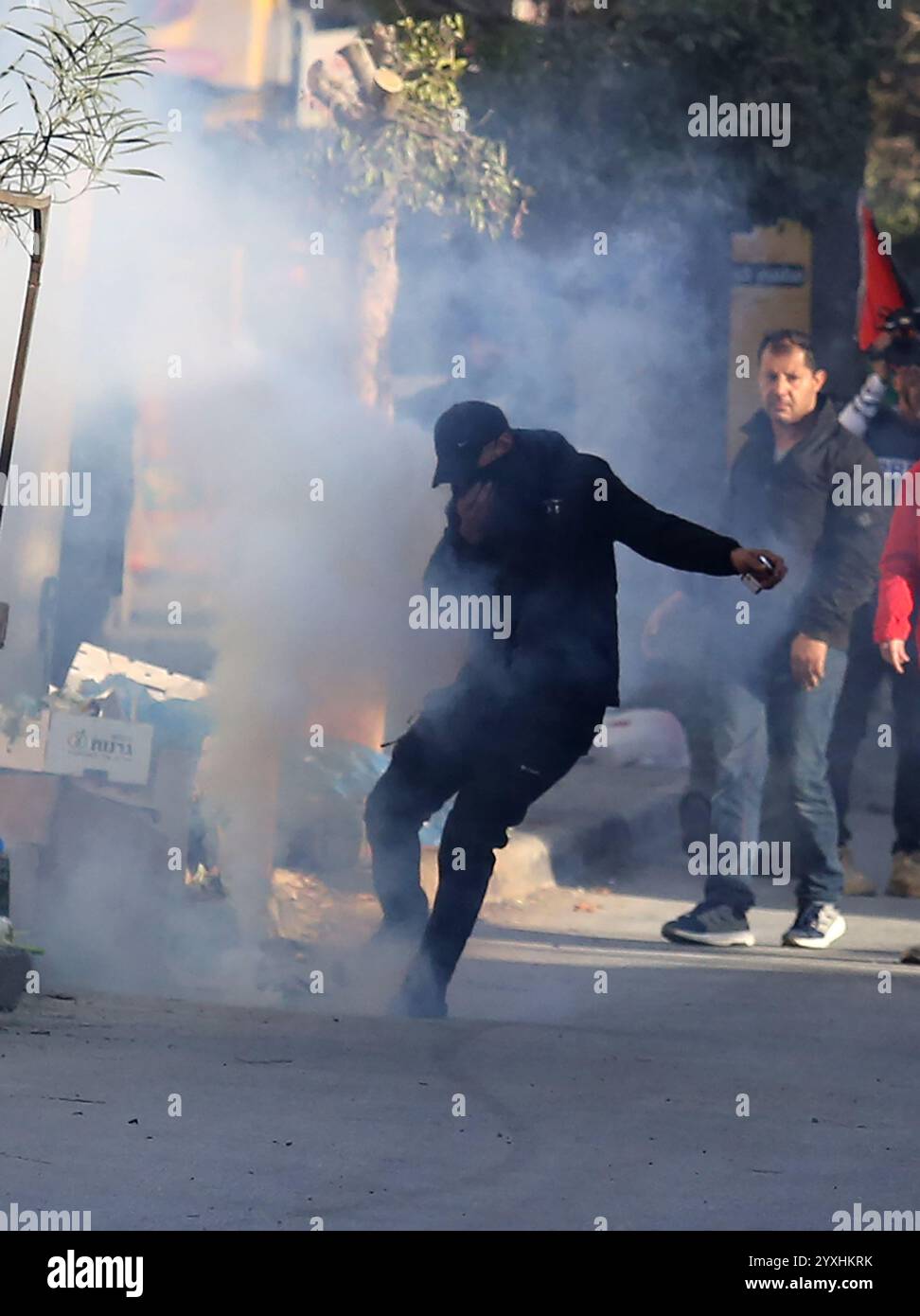 (241216) -- JENIN, 16 dicembre 2024 (Xinhua) -- Un manifestante cerca di calci una tanica di gas lacrimogeni lanciata dalle forze di sicurezza palestinesi durante una marcia che chiede la revoca dell'assedio al campo di Jenin, a Jenin, nella Cisgiordania settentrionale, il 16 dicembre 2024. Le forze di sicurezza palestinesi hanno assediato il campo profughi di Jenin sabato dopo che i militanti affiliati alla "Brigata Jenin” del movimento della Jihad islamica e altre fazioni palestinesi hanno sequestrato due veicoli appartenenti all'Autorità palestinese il 5 dicembre, secondo la fonte, che hanno richiesto l'anonimato. Crediti: Xinhua/Alamy Live News Foto Stock