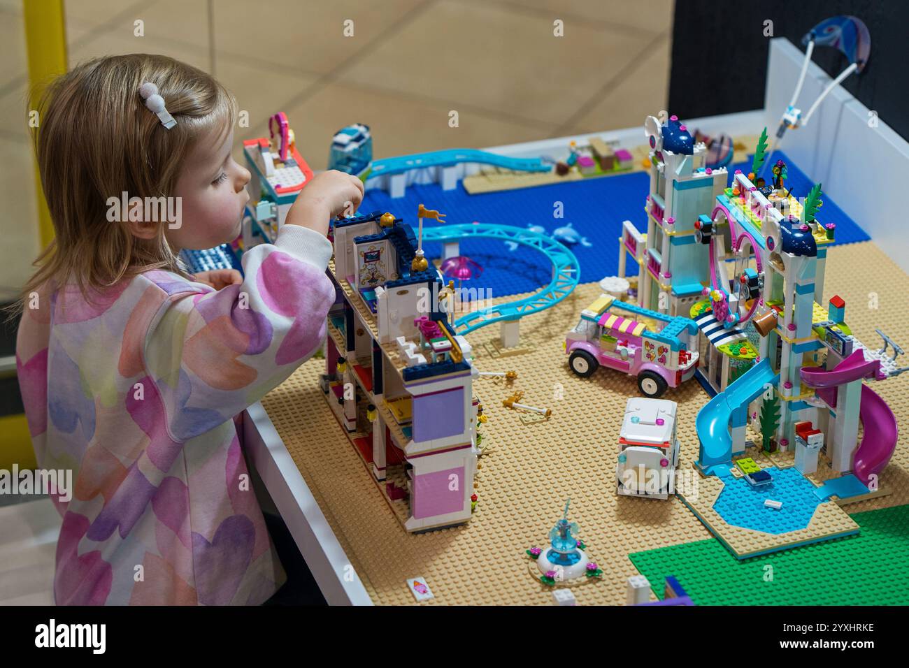 La bambina felice gioca con i giocattoli Lego nel centro giochi Lego. Giochi educativi - svago intellettuale per bambini. Minsk, Bielorussia - 24 novembre 2024 Foto Stock