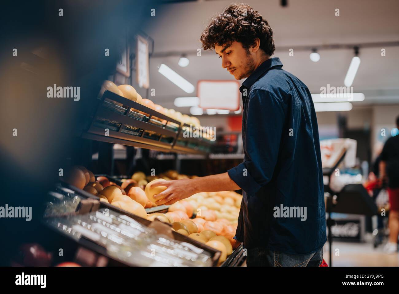 Giovane che sceglie la frutta in un negozio di alimentari Foto Stock