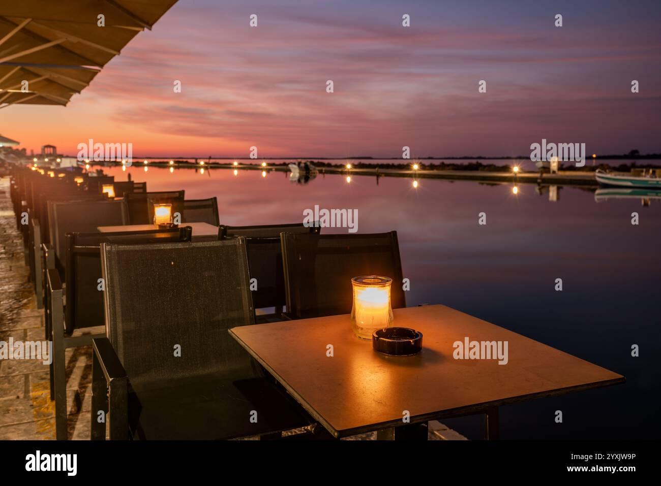 File di tavoli illuminati a lume di candela in una lanterna in un ristorante sul lungomare Foto Stock