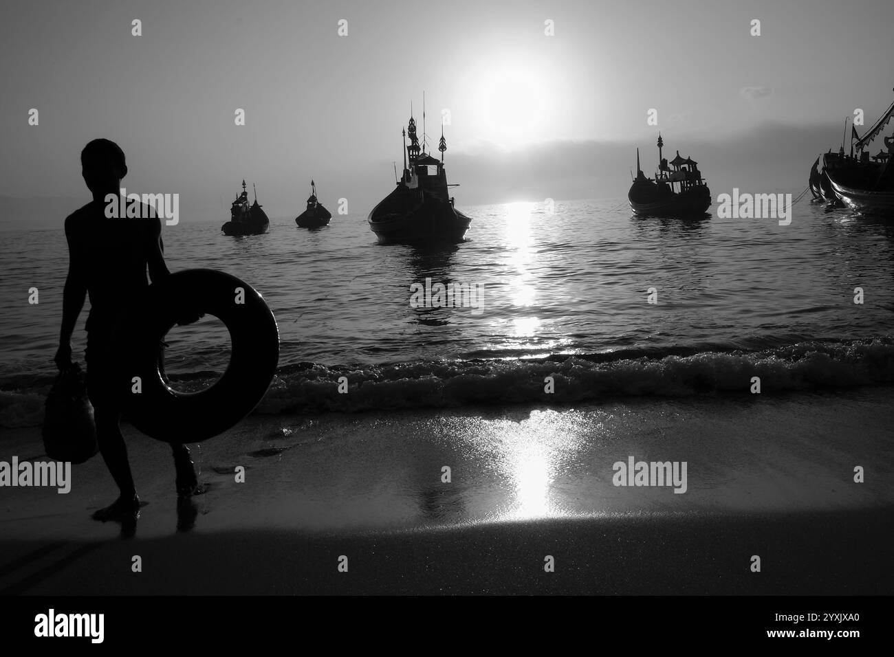 Sagoma dei pescatori che tornano dal mare e delle barche tradizionali che galleggiano nelle acque della spiaggia di Papuma. Foto Stock