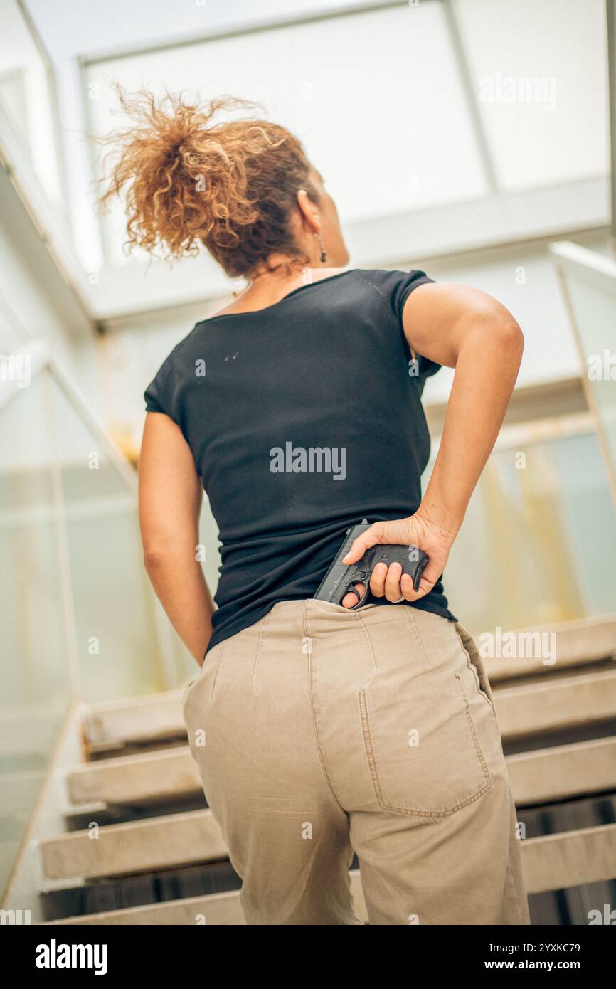 DONNA CON UNA PISTOLA, VISTA POSTERIORE Foto Stock