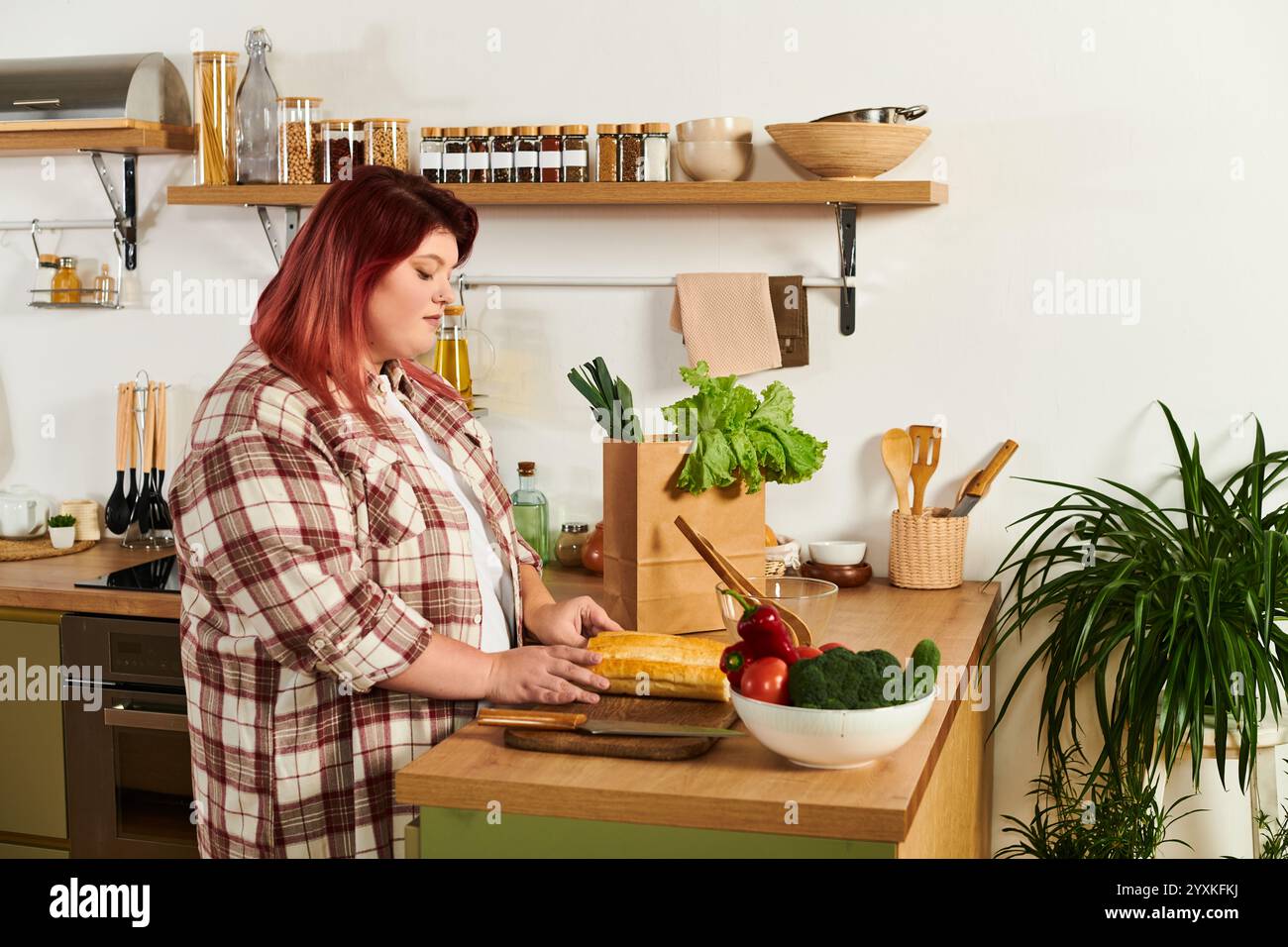 All'interno di una cucina calda, una giovane donna di grandi dimensioni prepara sapientemente ingredienti freschi per un pasto. Foto Stock