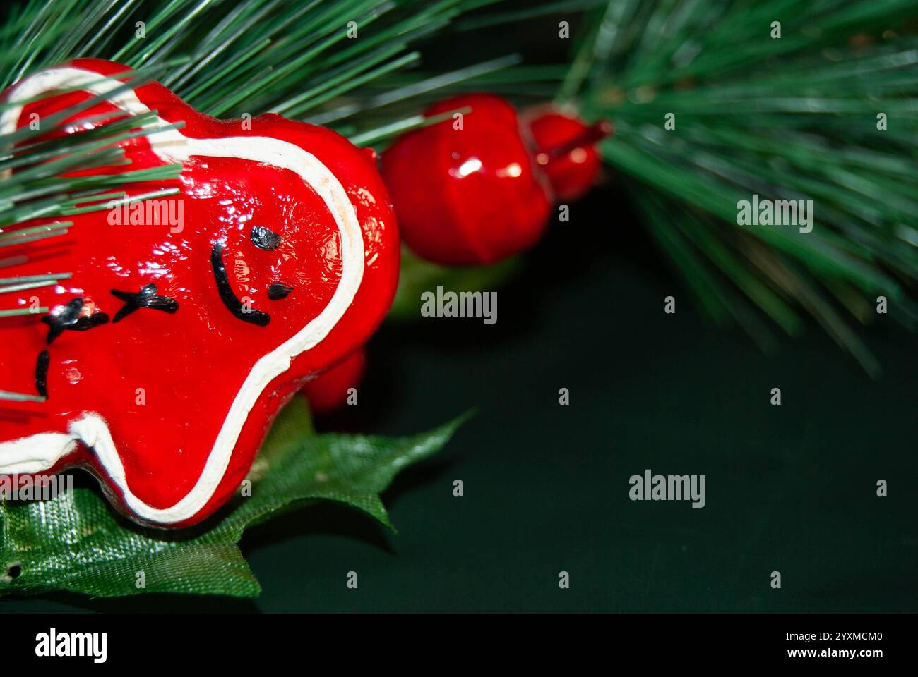 Biscotto decorativo rosso su sfondo verde con rami di pino. Foto Stock