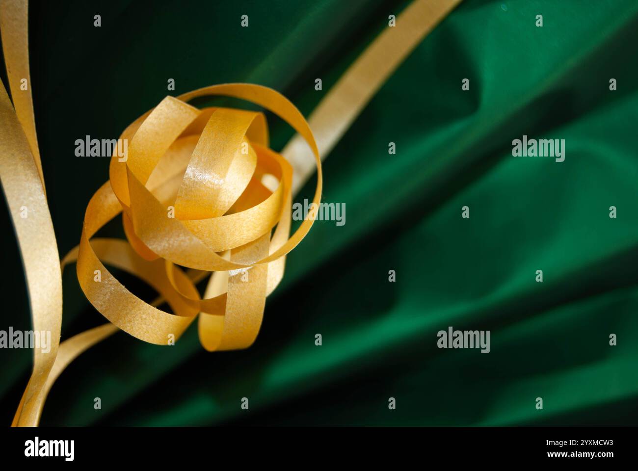 Fiocco regalo giallo brillante su carta da imballaggio verde, per creare uno sfondo colorato e festoso. Foto Stock