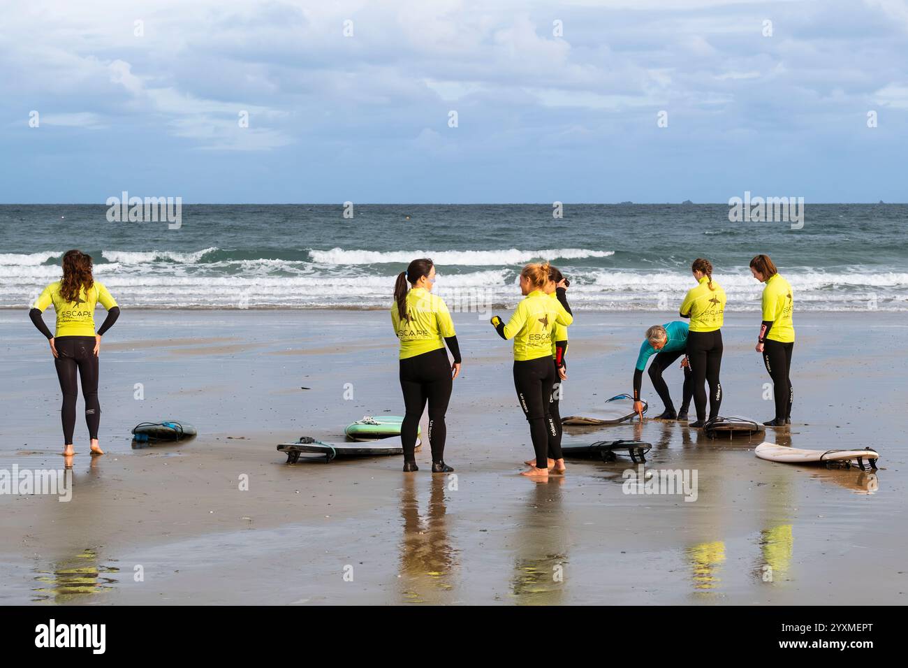 Un istruttore di surf della Escape Surfing School tiene una lezione di surf con un gruppo di studentesse a Towan Beach a Newquay in Cornovaglia nel Regno Unito. Foto Stock