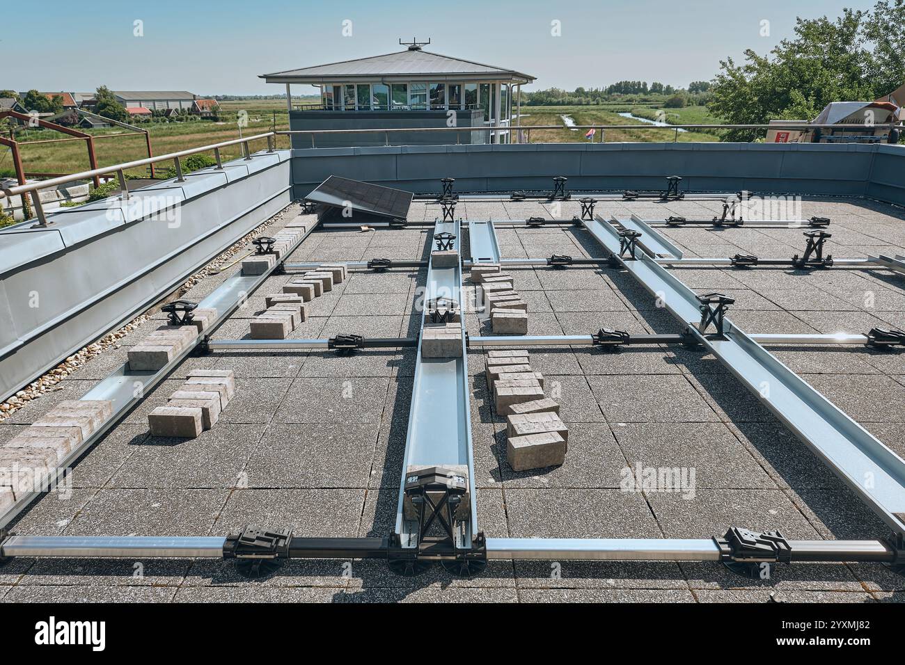 Terrazza sul tetto in costruzione con telai di montaggio a pannelli solari e mattoni per zavorra, che mette in mostra la tecnologia dell'energia pulita in un moderno ambiente urbano Foto Stock