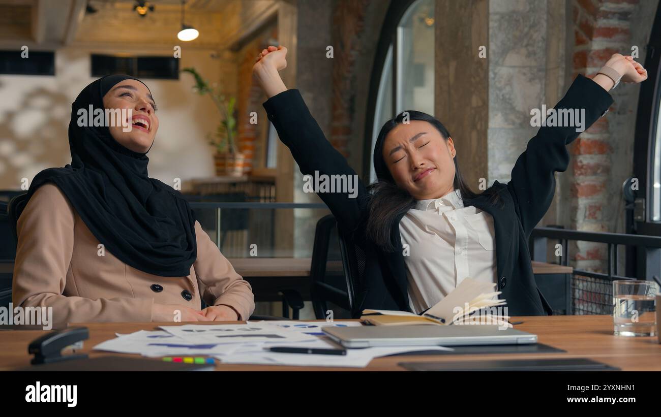 Due donne d'affari multirazziali donna asiatica coreana ragazza musulmana hijab islamico donna d'affari in ufficio sorridente fine videochiamata conferenza portatile Foto Stock
