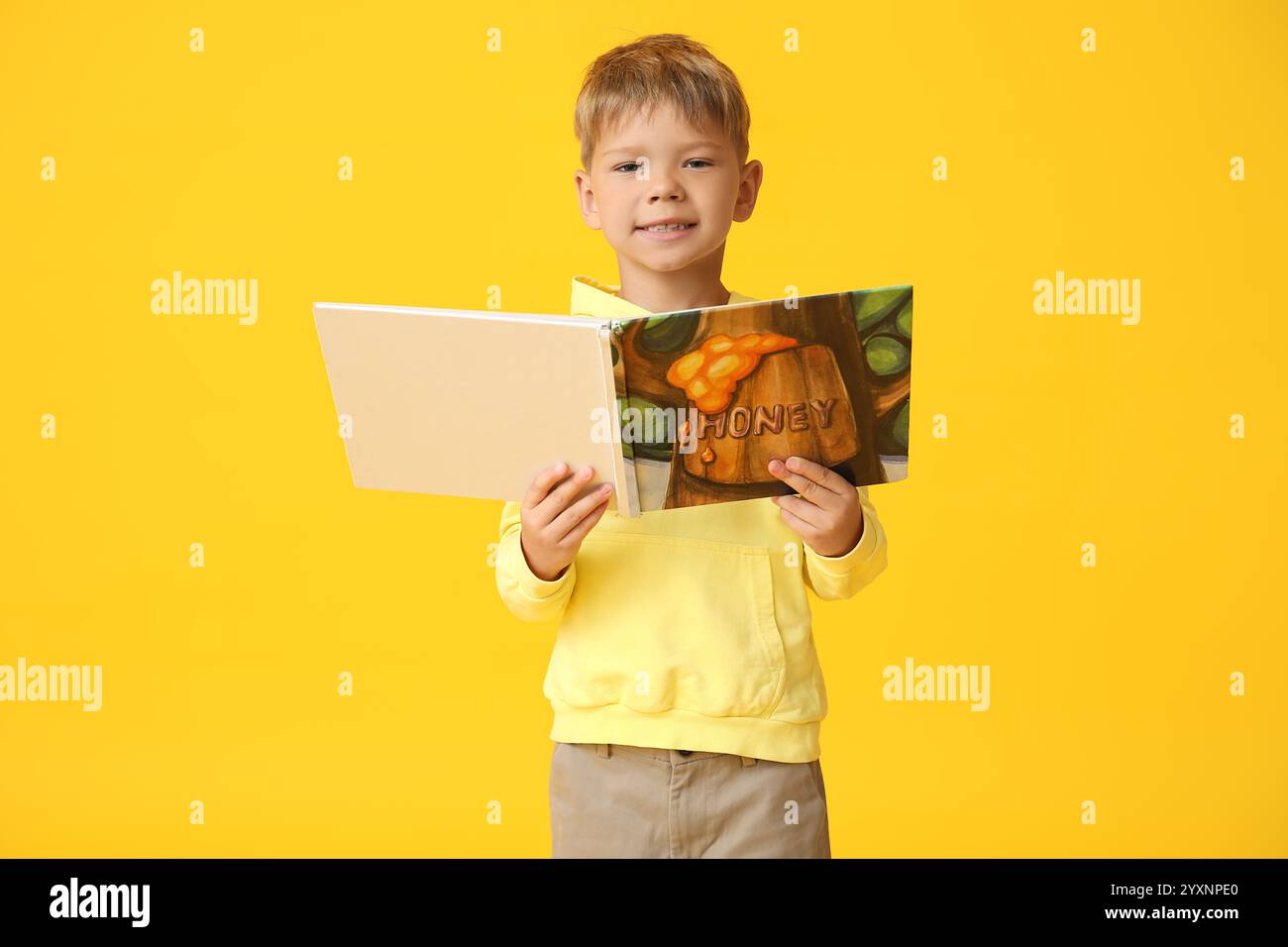 Ritratto di un bambino sorridente con libro su sfondo giallo Foto Stock