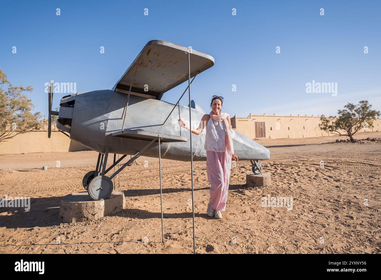 Una bella donna di mezza età posa all'ingresso di un hotel nel deserto del Sahara nella regione di Merzouga, Marocco. E' il piccolo aereo usato nel Foto Stock