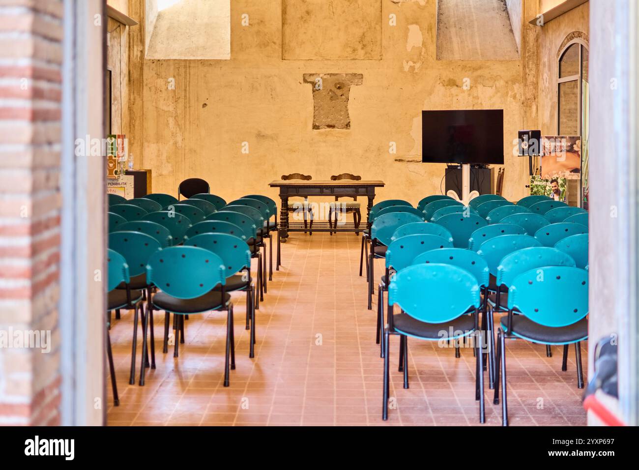 Savona. Italia - 17 dicembre 2024: File di sedie blu disposte ordinatamente in una sala conferenze vuota. Concetto: Perfetto per eventi, riunioni o seminari Foto Stock