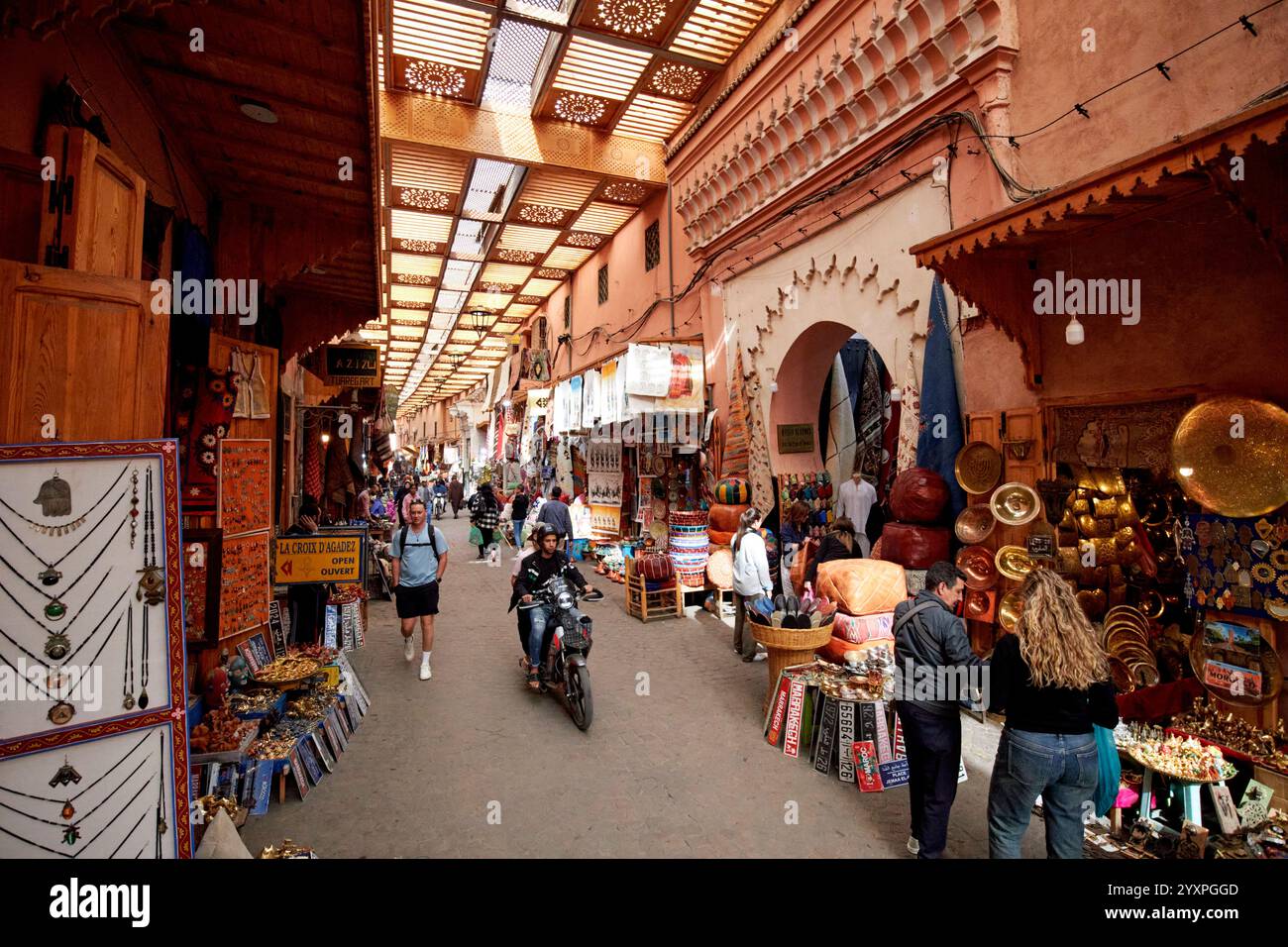 guida in moto lungo la strada coperta nel suk con negozi di artigianato in rue fehl chidmi marrakesh, marocco Foto Stock