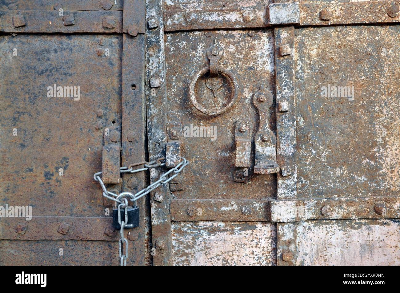 Elemento di una vecchia porta in acciaio con una catena moderna con serratura. Foto Stock