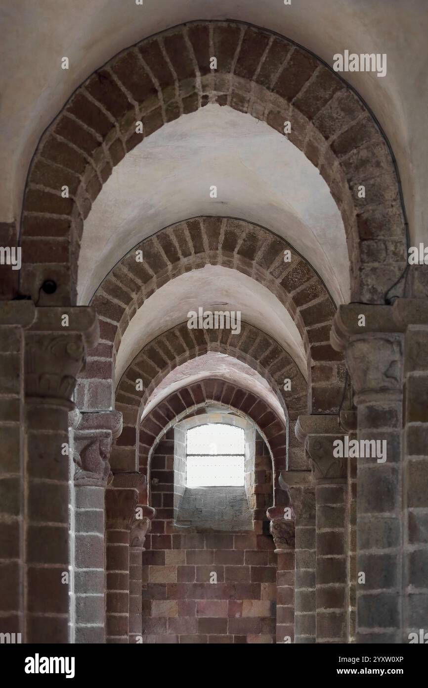 119 archi in muratura a blocchi di pietra leggermente appuntiti che formano una galleria che conduce ad una finestra esterna a lucernario, la chiesa di Mont-Saint-Michel. Normandia-Francia. Foto Stock