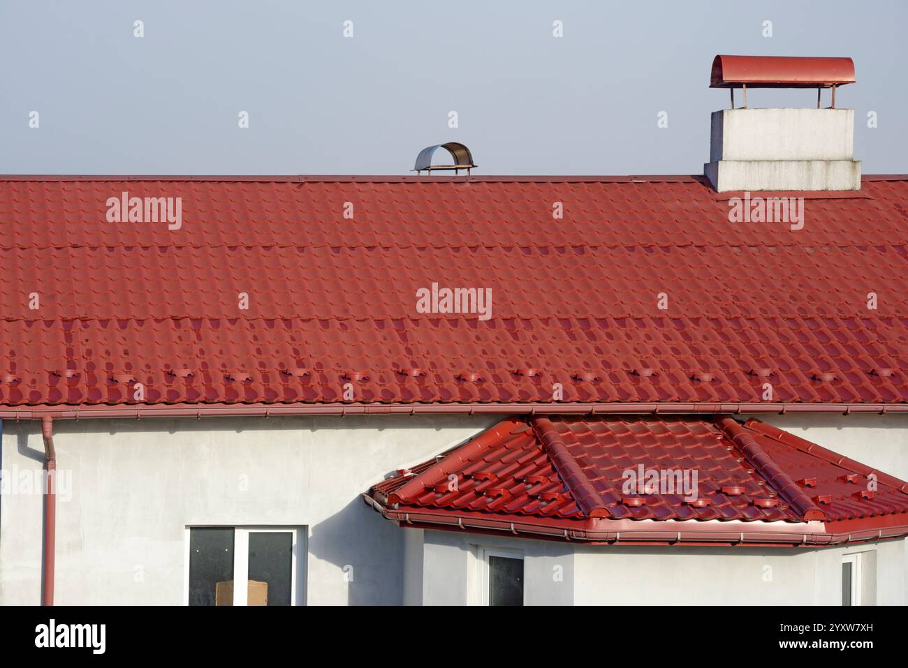Pendenza del tetto coperta da lamiere di metallo effetto piastrella di colore rosso brillante. Foto Stock