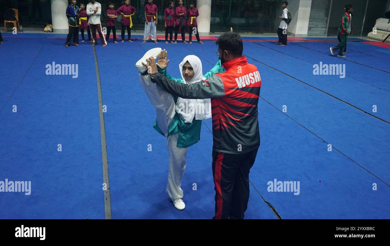 Dacca. 18 dicembre 2024. Una giocatrice di Wushu pratica sotto la guida in uno stadio al coperto nel distretto di Cox's Bazar, Bangladesh, 19 novembre 2024. Negli ultimi anni, il cinese Wushu è diventato uno degli sport popolari del Bangladesh, specialmente nel distretto di Cox's Bazar, che è emerso come un centro di giocatori nazionali Wushu. PER ANDARE CON "Feature: Il Bangladesh's Cox's Bazar diventa hub emergente per Wushu" credito: Xinhua/Alamy Live News Foto Stock