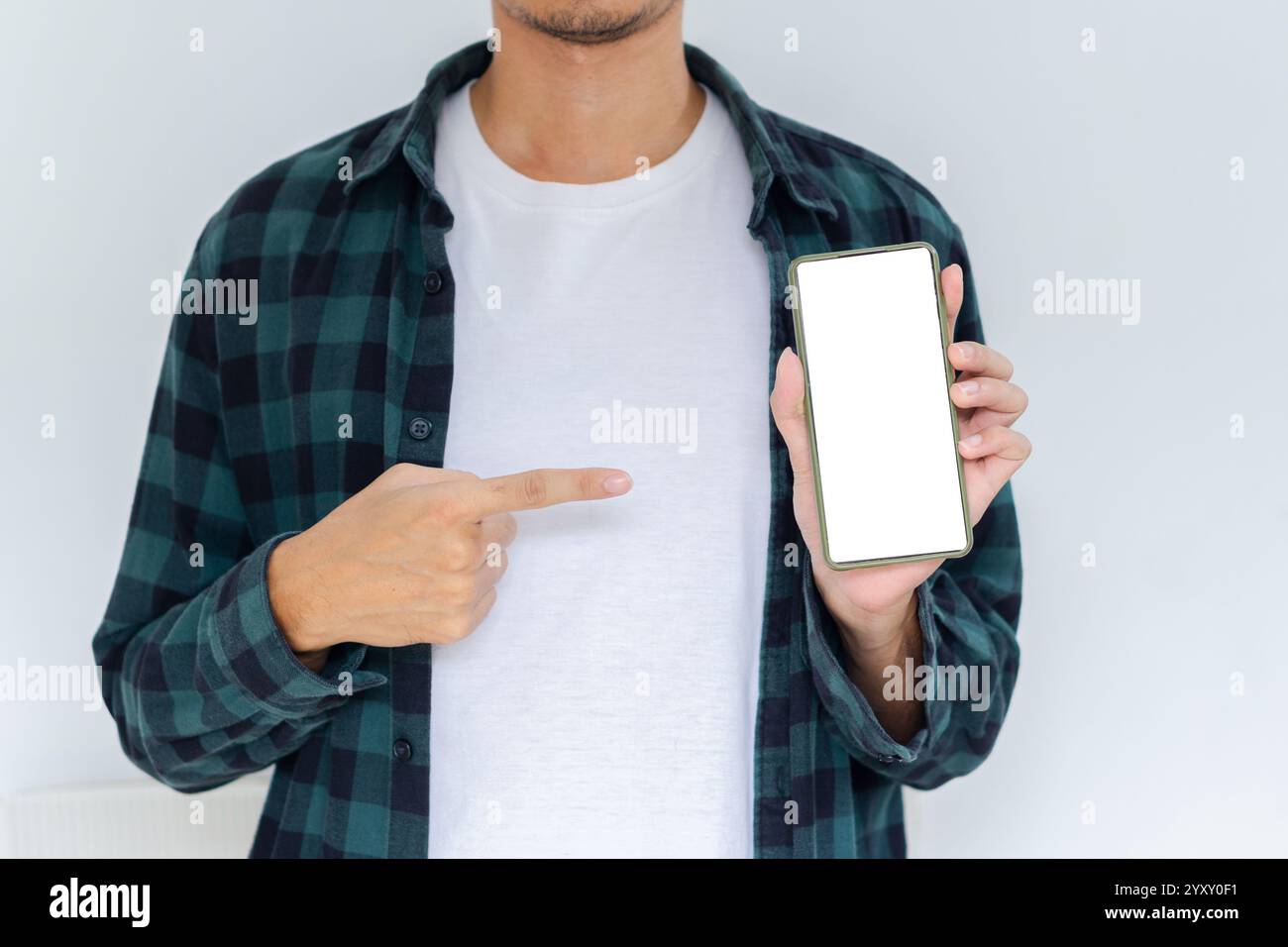 Corpo a metà corta giovane adulto con flanella e camicia bianca che punta al telefono con sfondo bianco isolato Foto Stock