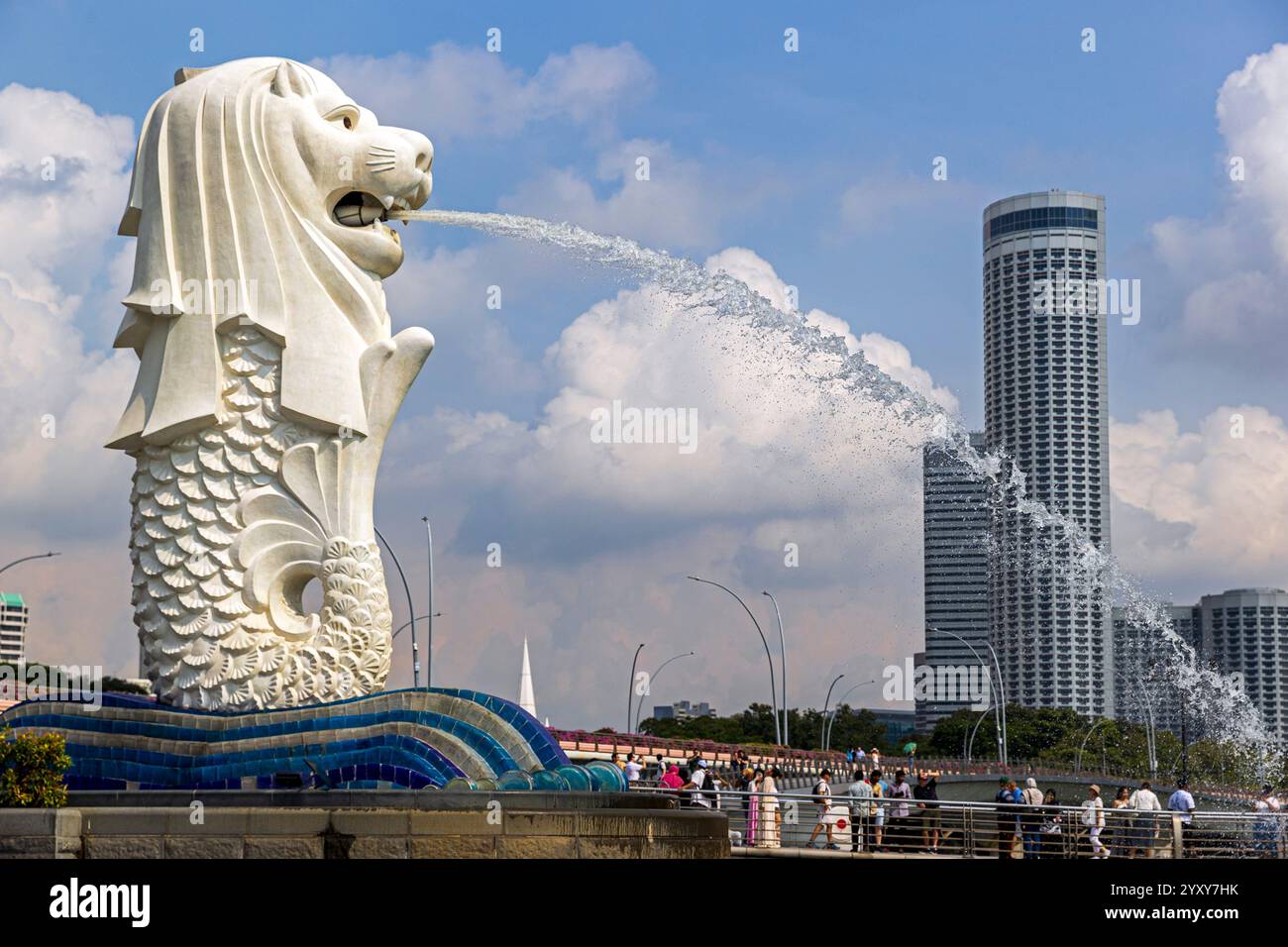 Statua del Merlion al Merlion Park di Singapore che sprigiona acqua contro un cielo azzurro limpido con nuvole soffici. Foto: David Rowland / One-Image.com Foto Stock