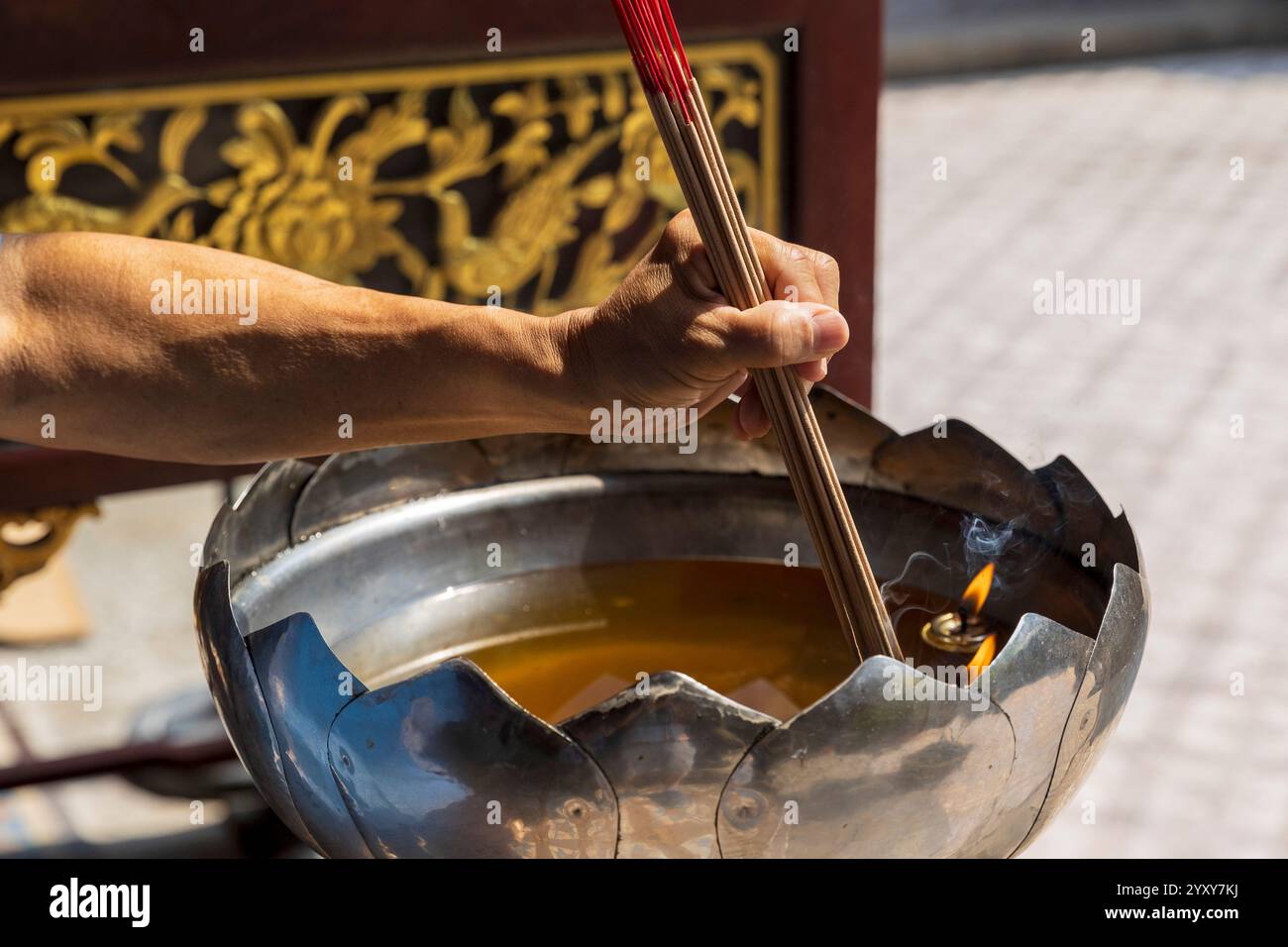 Un braccio posiziona i bastoncini di incenso in una fiamma, Thian Hock Keng Temple, Singapore, foto: David Rowland / One-Image.com Foto Stock
