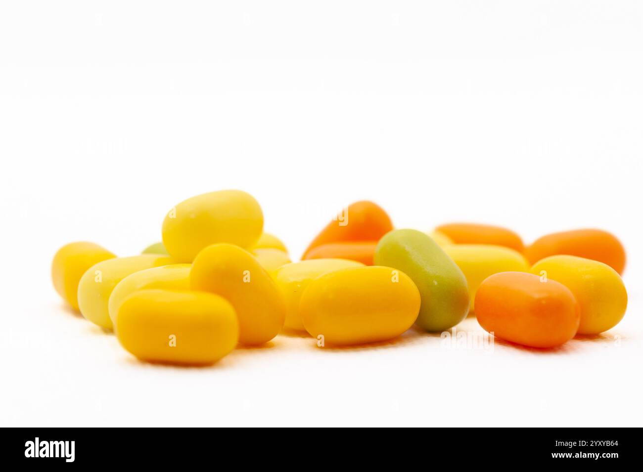 Una pila di caramelle con pezzi gialli, verdi e arancioni. Le caramelle hanno la forma di una palla Foto Stock