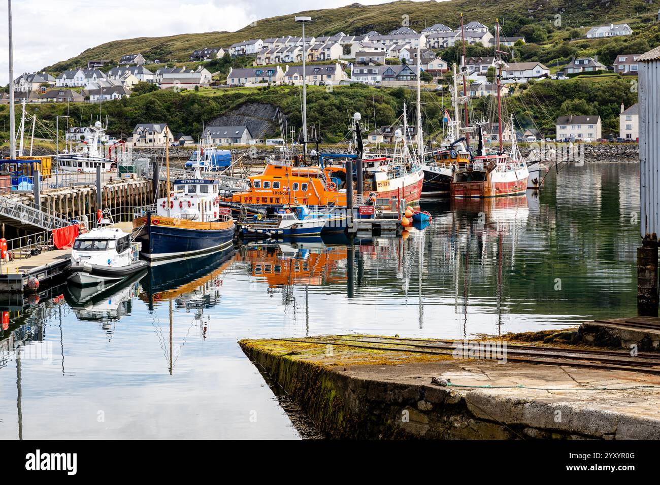 Calm Harbour con Lifeboat, barche da pesca e Hillside residenziale Foto Stock