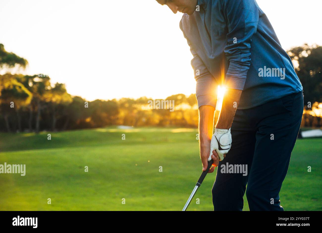 Giocatore di golf maschile che gioca a golf dal tee box allo splendido tramonto Foto Stock