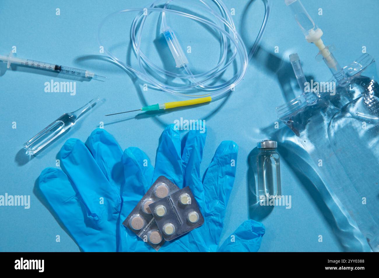 Sacca per infusione, siringa, fiale mediche su sfondo blu. Camera di gocciolamento IV Foto Stock