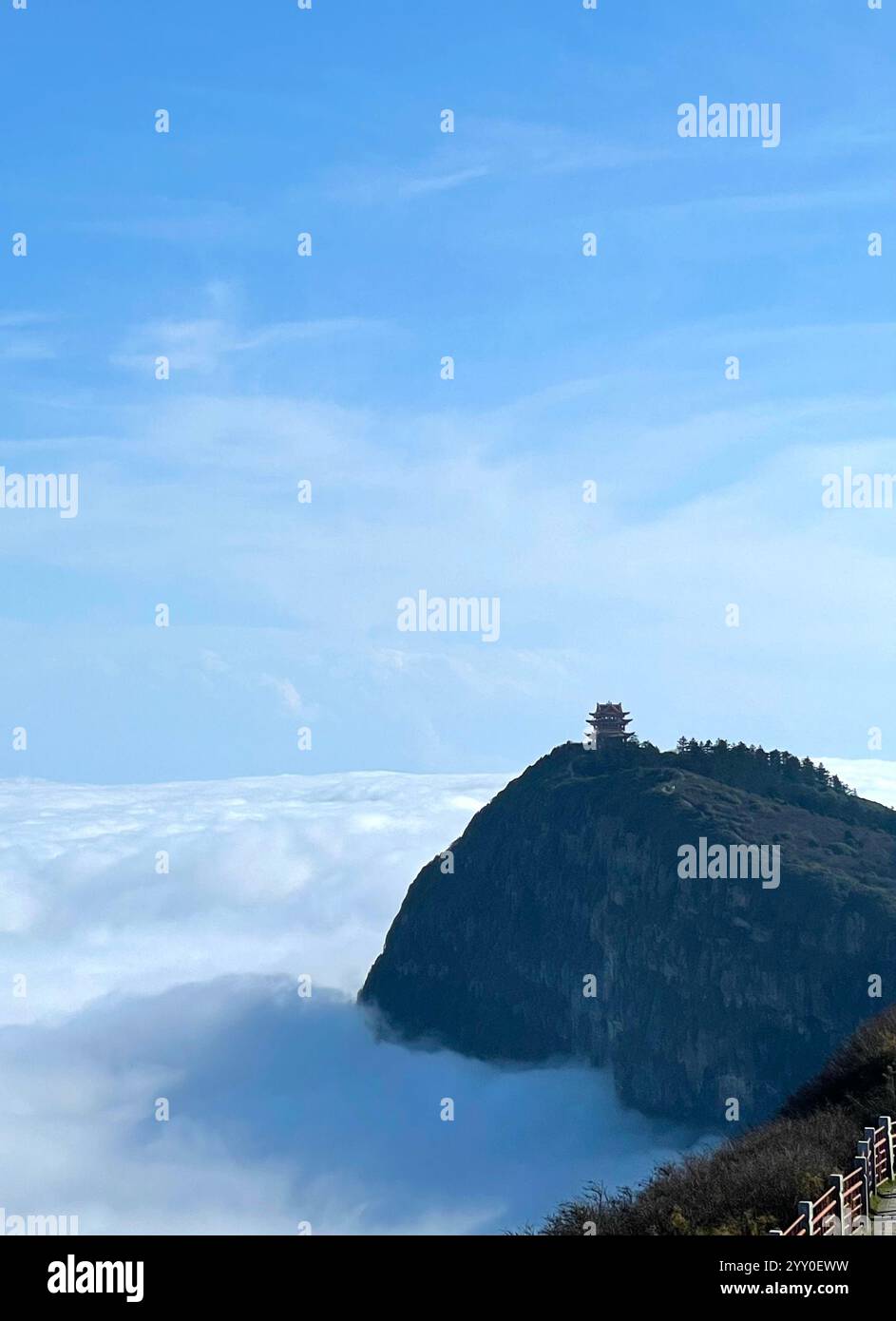 Piccolo tempio cinese sulla cima di una montagna circondato da un mare di nuvole e un cielo blu - Immagine stock catturata con smartphone