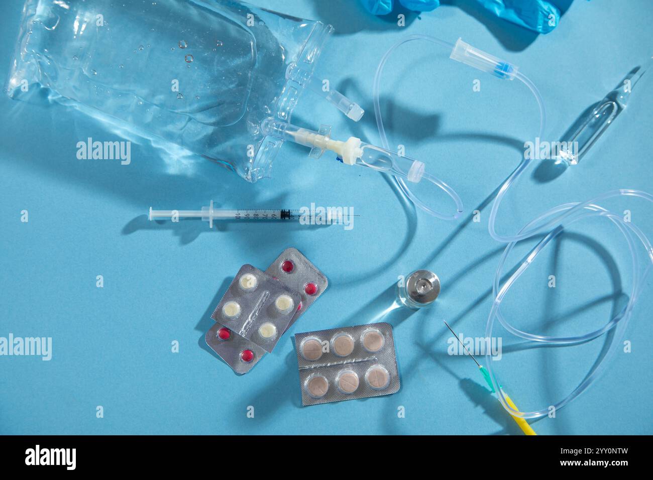 Sacca per infusione, siringa, fiale mediche su sfondo blu. Camera di gocciolamento IV Foto Stock