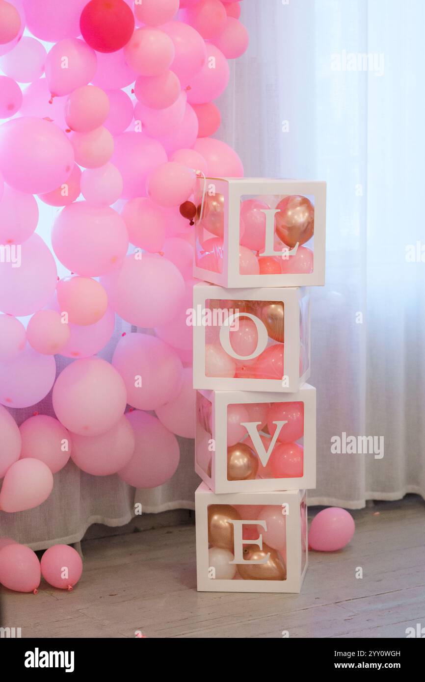 Cubi di legno con la parola "amore" sullo sfondo di palloncini rosa, NATURA MORTA ROSA ROSA Foto Stock