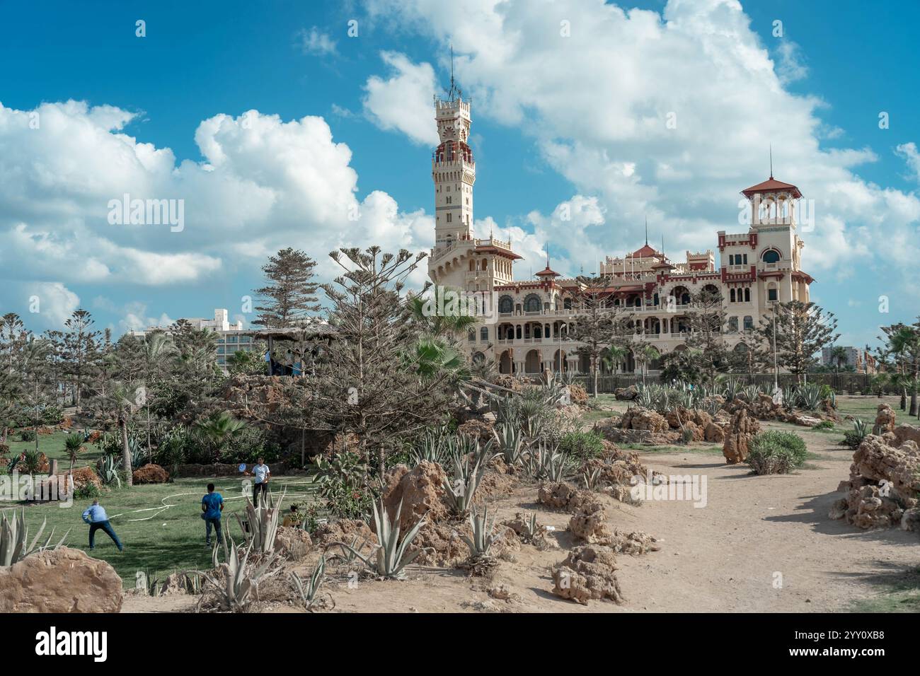Palazzo di Montaza ad Alessandria, in Egitto, circondato da giardini lussureggianti e rocce desertiche, sotto un cielo blu brillante. Architettura storica e paesaggio. Foto Stock