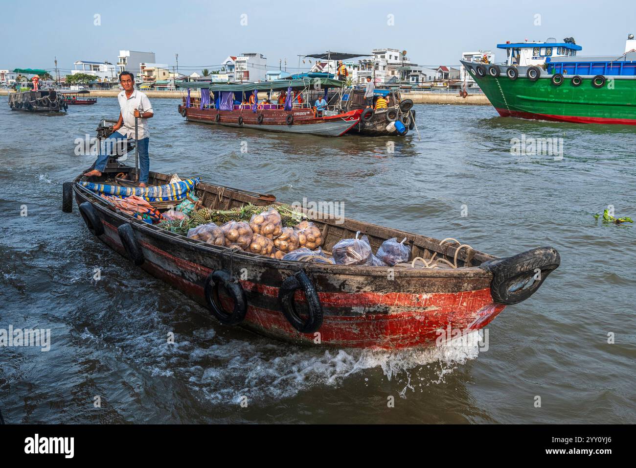 Vietnam, 2024-03-03, delta del Mekong, barca, mercato galleggiante, trasporto, cibo, barca, venditore, frutta, verdure, fiume, onde, sole, ombre, merchandising Foto Stock