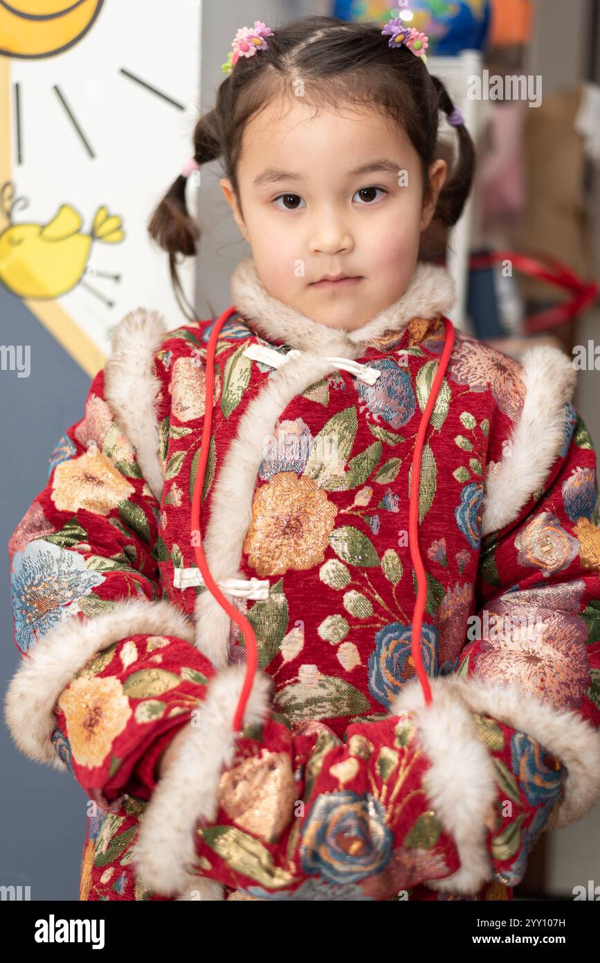 Bella ragazza multirazziale di 4 anni è pronta per una celebrazione del Capodanno cinese. Sta posando per una foto nel suo vestito tradizionale cinese Foto Stock