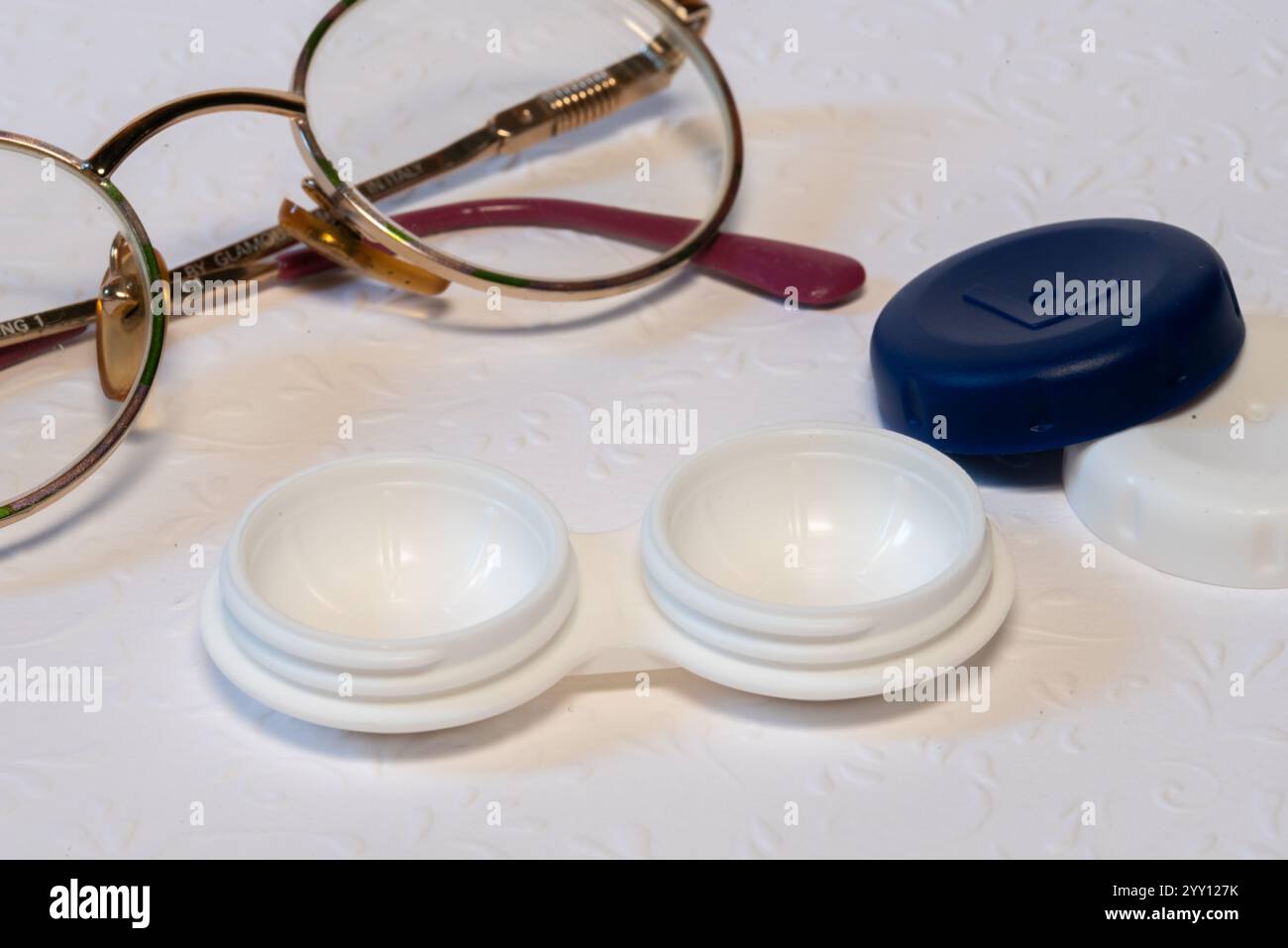 occhiali e supporto per lenti a contatto su sfondo bianco, vista dall'alto Foto Stock