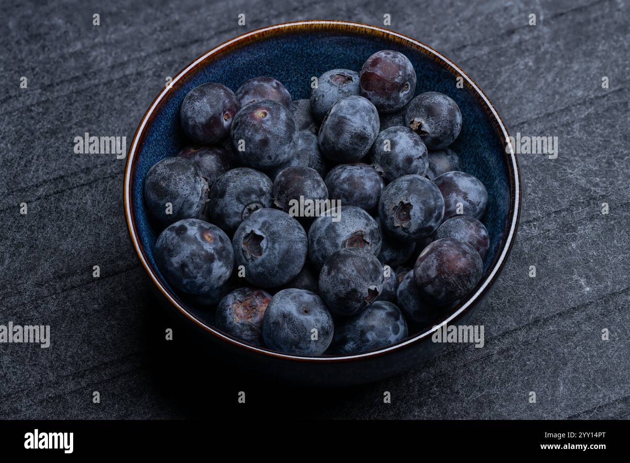 , Deutschland, 18.12.2024, Nahaufnahme von frischen Blaubeeren in einer blauen Keramikschale auf dunklem Hintergrund. Gesundes Obst, ideale für Ernähr Foto Stock