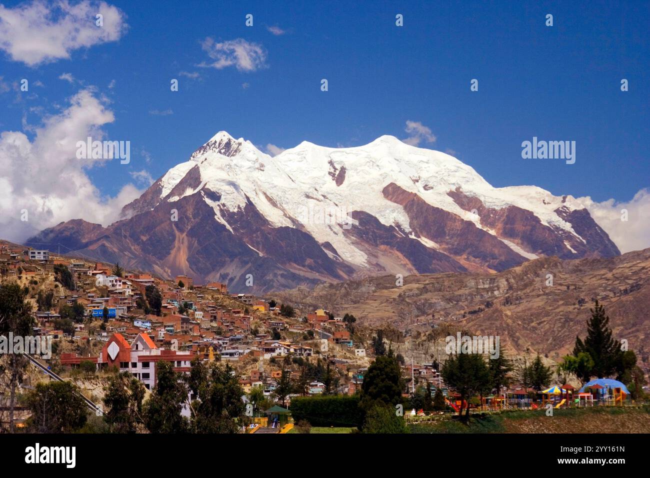 Maestosa montagna Illimani coperta di neve, che torreggia sulla città di la Paz, Bolivia. Il contrasto tra il paesaggio urbano e la bellezza naturale Foto Stock