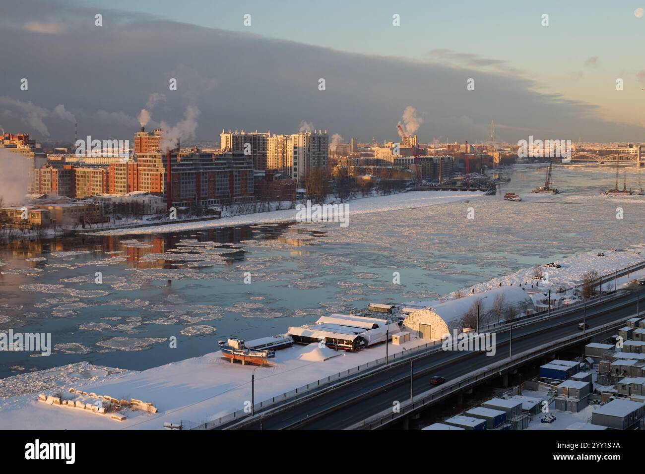 Una splendida vista invernale sul fiume con ghiaccio denso, edifici suggestivi e uno splendido skyline in lontananza Foto Stock