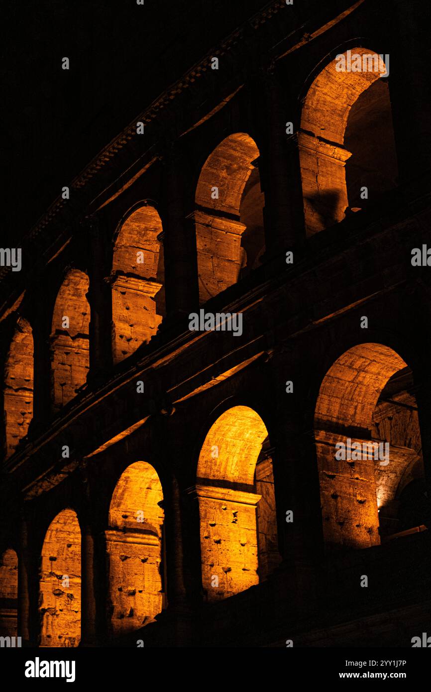 Spettacolare veduta notturna del Colosseo di Roma, illuminato dalla luce arancione, contrasto elevato, splendida architettura, splendida scena italiana Foto Stock