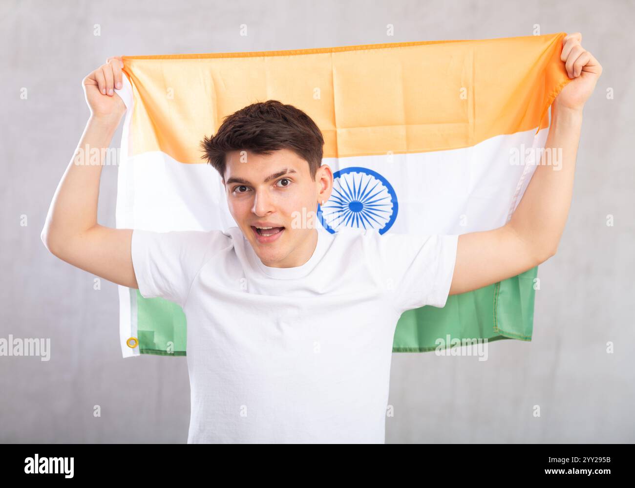 Lo spettatore maschio attivo e pieno di energia tiene in mano la bandiera nazionale dell'India e canta slogan popolare. Foto Stock