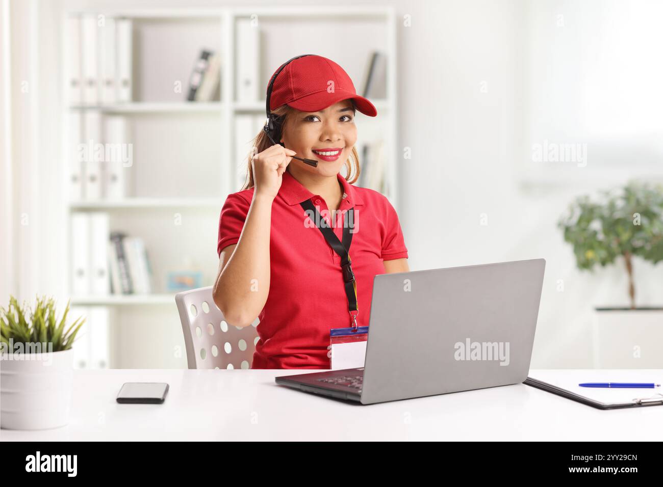 Lavoratrice asiatica in un centro di gestione delle chiamate che lavora con un computer portatile Foto Stock