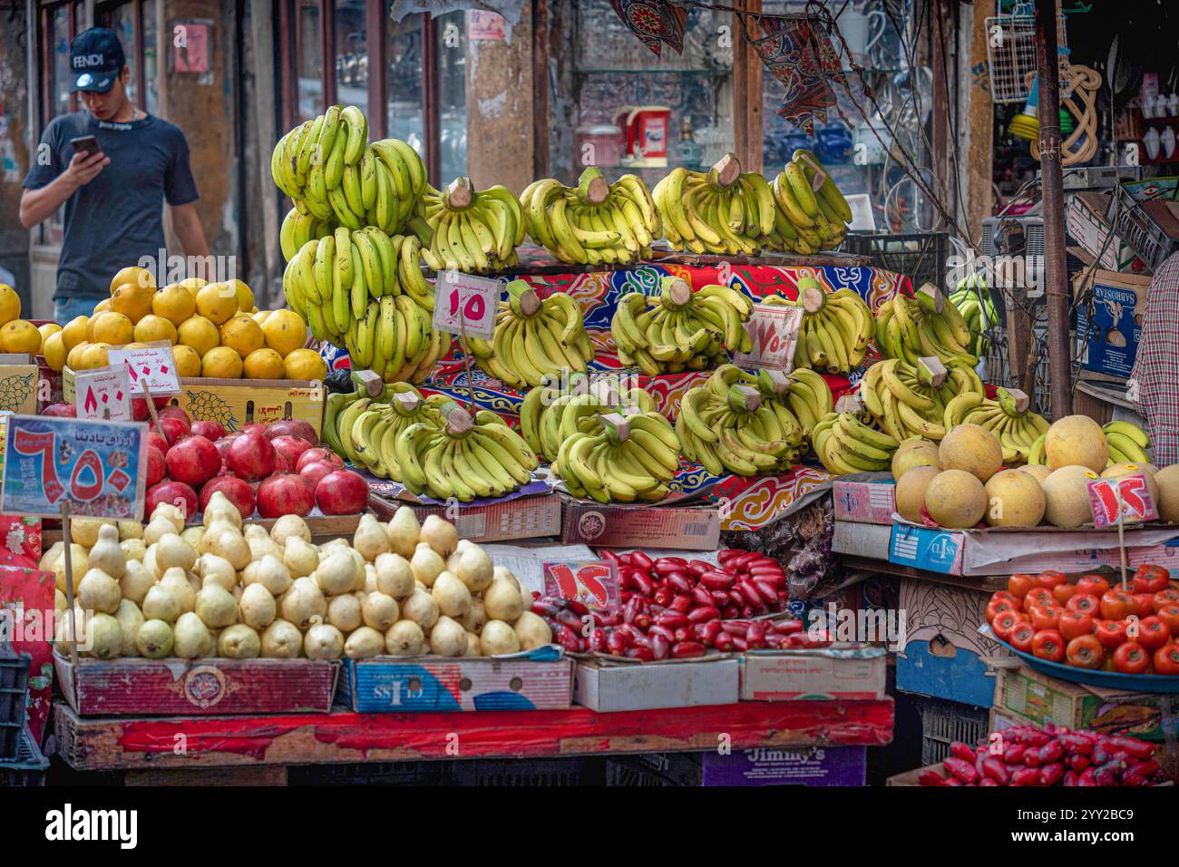 Un banco di frutta colorato ad Alessandria, Egitto, che espone banane mature, pere, melograni, e peperoni in un vivace mercato tradizionale. Foto Stock