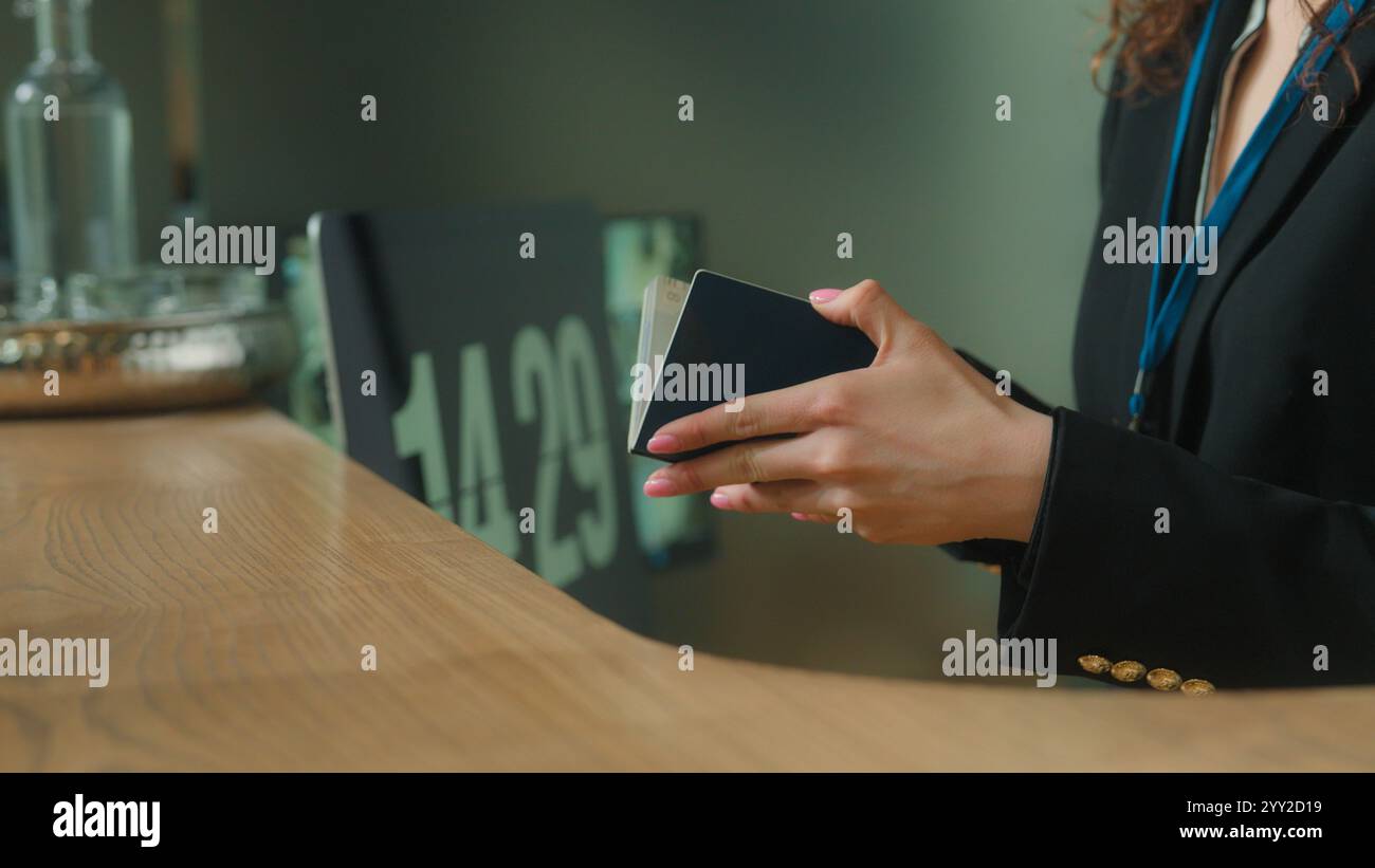 Donna irriconoscibile concierge operaio reception dell'hotel dare il controllo dei biglietti aerei servizio di registrazione passaporto viaggiatore turista arrivo passeggero Foto Stock