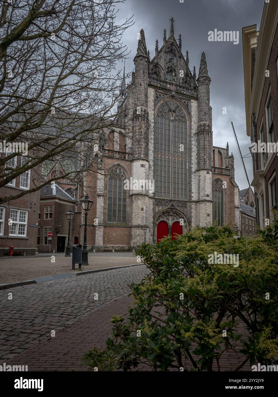 La chiesa in stile gotico di Hooghlandse, Leida, con alte e intricate finestre e porte rosse, si erge in modo prominente alla fine di una strada acciottolata, circondata Foto Stock