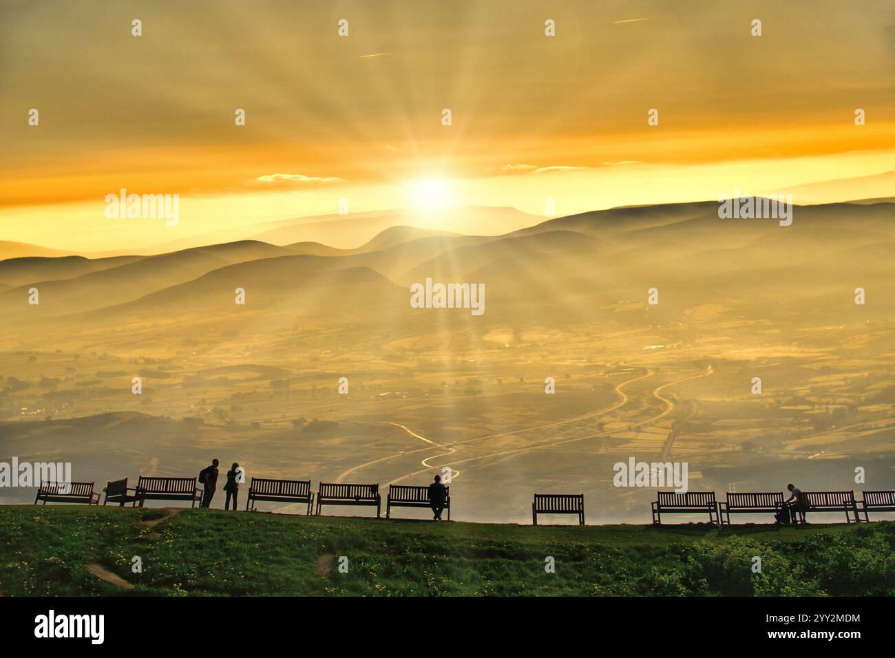 Guardare il sole tramontare sulle colline della Cumbria bagnate da raggi di sole Foto Stock