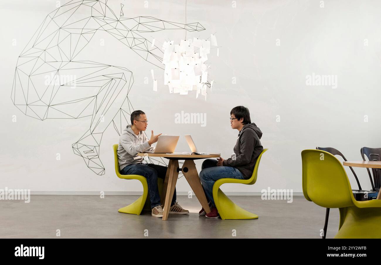 Monaco di Baviera, Germania - 04 febbraio. 2013: Un team creativo che si riunisce in un ufficio moderno a Monaco di Baviera con due giovani sconosciuti. Foto Stock