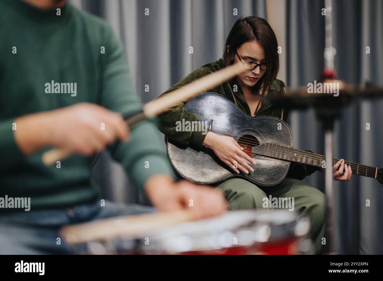 Musicisti che praticano insieme alla chitarra e alla batteria in studio di prova Foto Stock