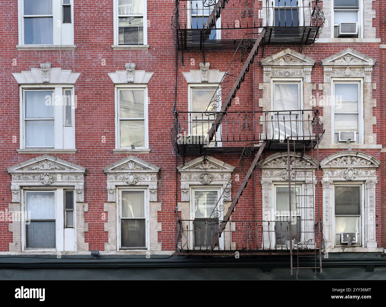 New York City, vecchio edificio di appartamenti con scala antincendio esterna e intagli ornamentali intorno alle finestre Foto Stock