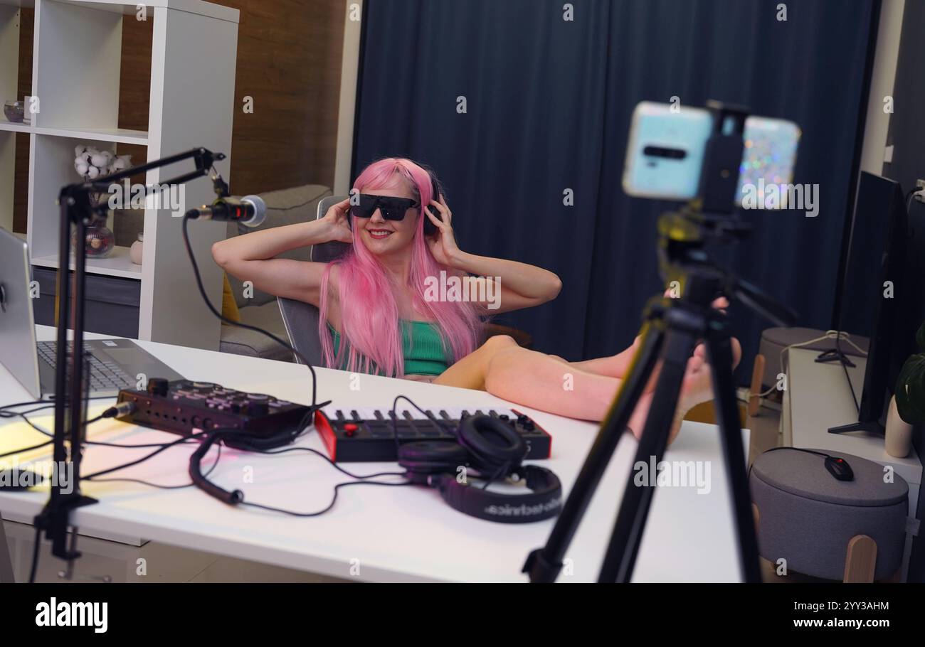 Bella giovane cantante e musicista trasmette dal suo studio di casa Foto Stock