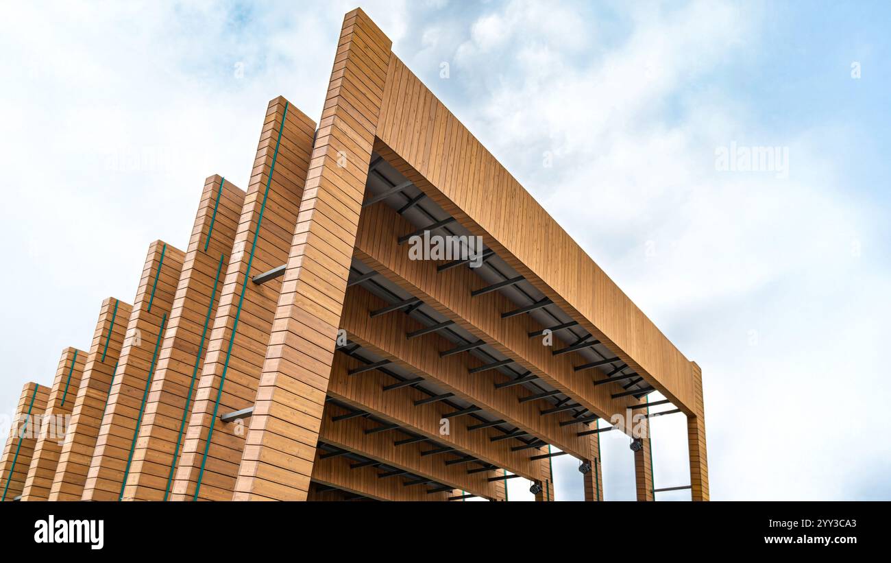 Moderno design architettonico in legno di palcoscenico all'aperto con travi sovrapposte e spazi aperti contro un cielo blu nuvoloso. Concetto di architettura contemporanea Foto Stock