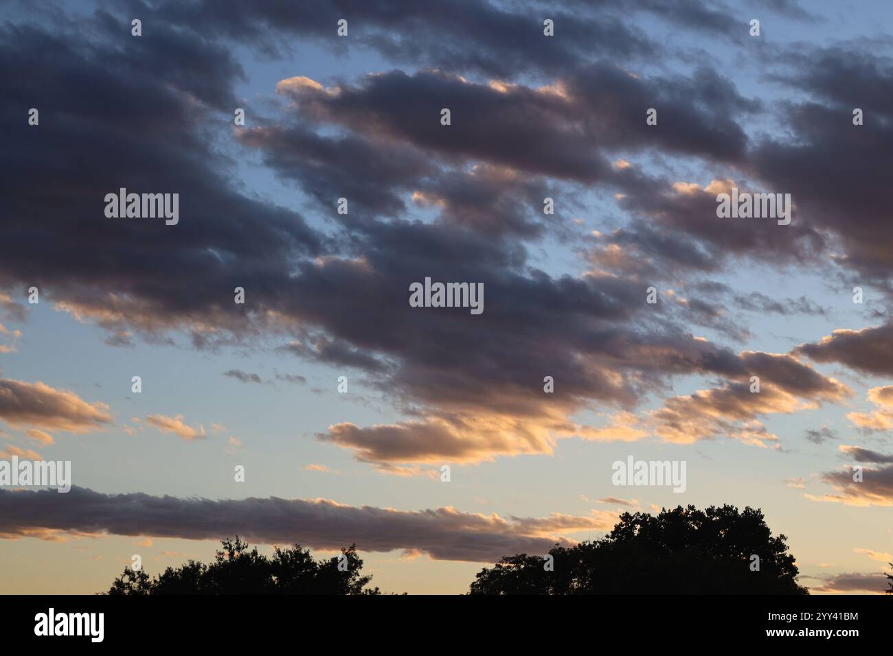 nuvole sparse scure sotto e bianche sopra al tramonto Foto Stock